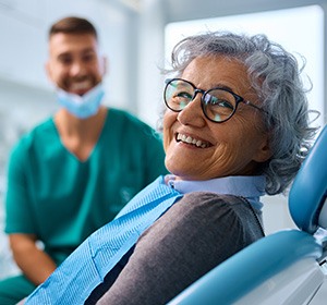 Woman with black glasses smiling in treatment chair