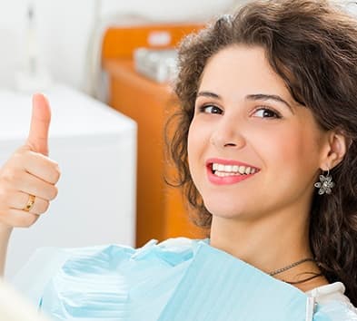 Woman in dental chair giving thumbs up