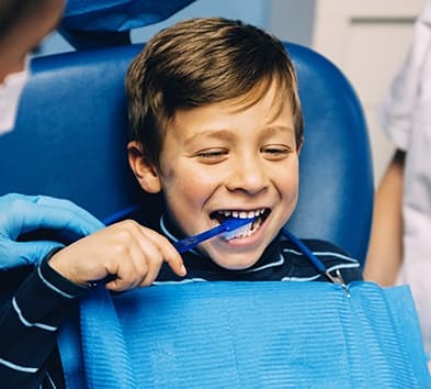 Child in dental chair practicing tooth brushing