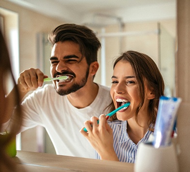 Couple preventing dental emergencies in Alexandria by brushing