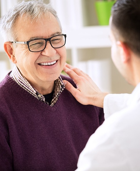 Implant dentist in Alexandria speaking to a smiling patient.