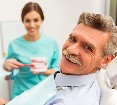 Smiling patient with dental implants in Alexandria visiting a dentist.