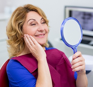 Older woman with dental implants in Alexandria examining her smile.
