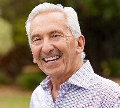 An older man with dental implants in Alexandria smiling.