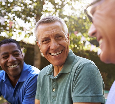 A group of older men smiling outside.