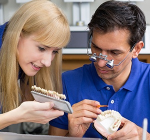 Dentist and assistant examining ceramic shades for dental implants in Alexandria.