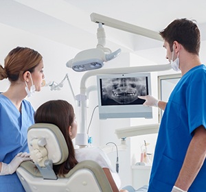 Assistant and Implant dentist in Alexandria showing patient an X-ray.