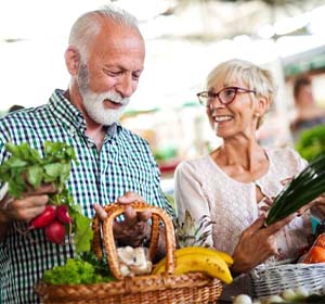 senior man and woman holding baskets of fruits and vegetables