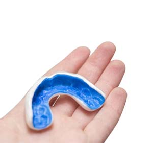 person holding a blue mouthguard in their hand