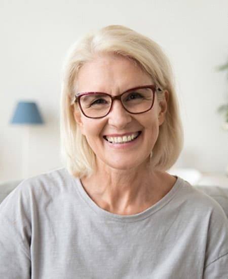 smiling senior woman with implant dentures in Alexandria, IN 