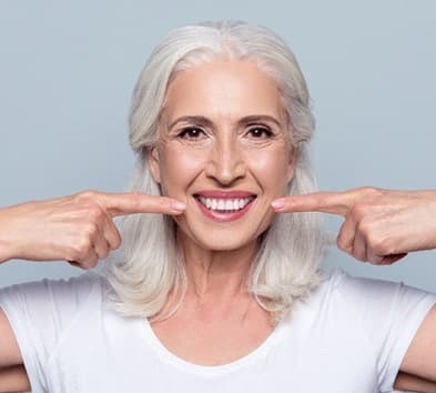 senior woman pointing to her smile  
