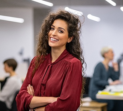 Woman standing in the middle of an office smiling 