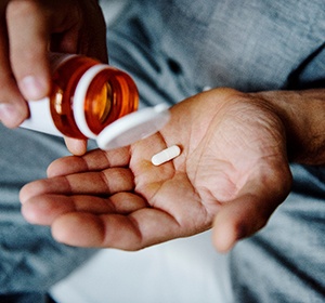 Man taking pain medication out of the bottle