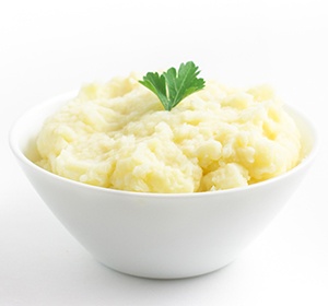 Bowl of mashed potatoes with a sprig of parsley