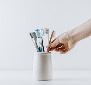 Hand taking one of several toothbrushes out of its holder