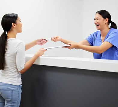 Friendly dental team member handing clipboard to patient