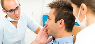 Man in dental chair holding cheek