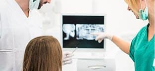 dentist patient and team member looking at x-rays