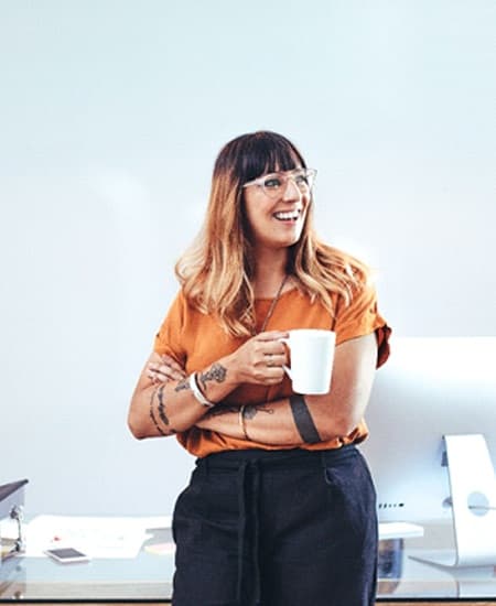 person smiling and holding a cup of coffee