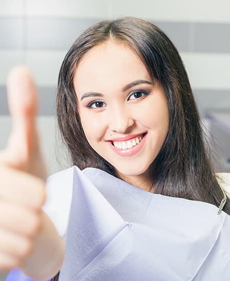 Young woman in dental chair giving thumbs up