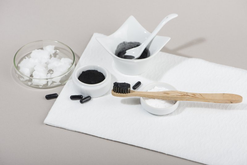 a toothbrush and charcoal being used in preparation to clean teeth