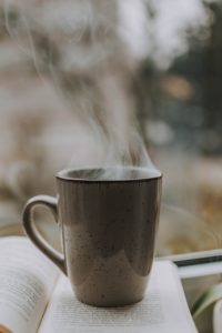 Steaming cup of coffee on an open book